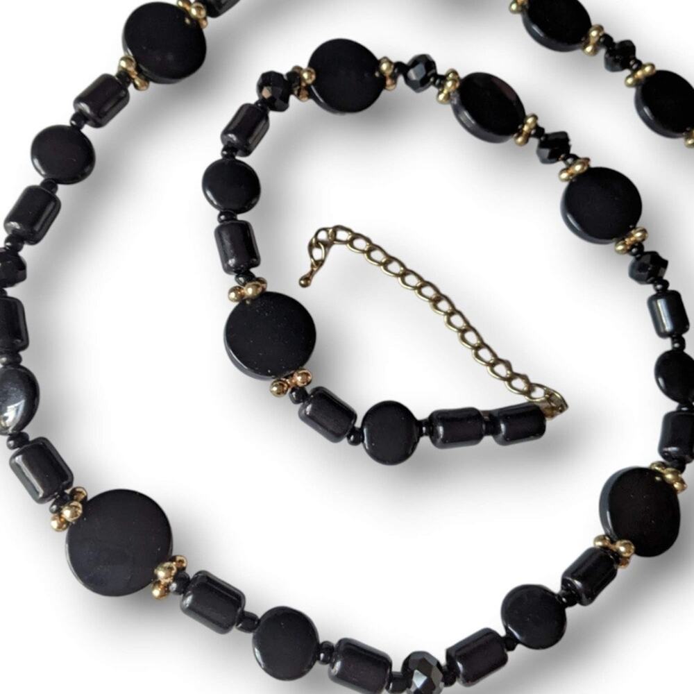 Long black plastic beaded necklace, black discs, gold tone accents